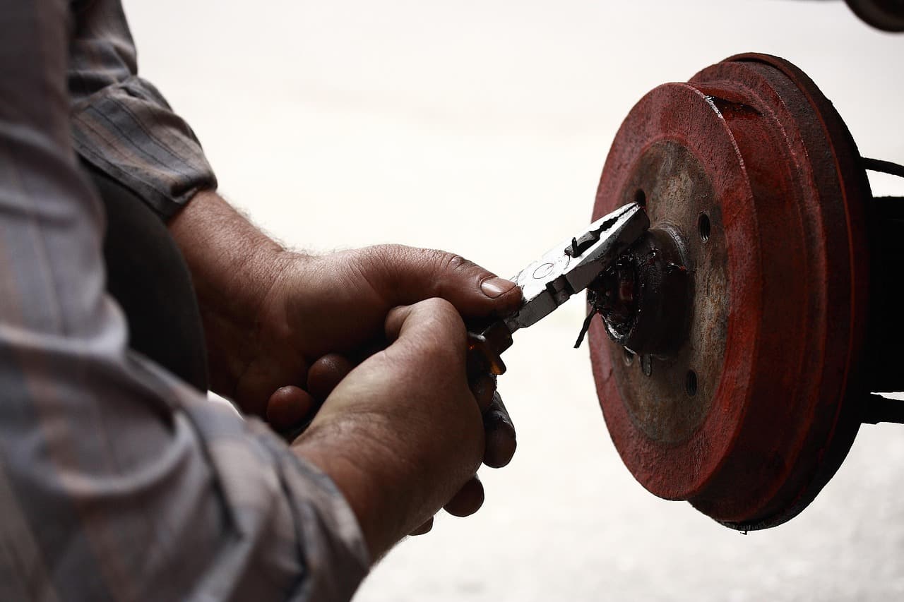 A mechanic’s hands working on a brake drum with pliers