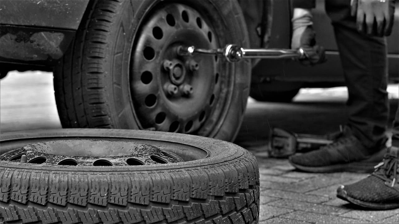 A wheel being changed with a wheel brace, the spare tyre on the ground