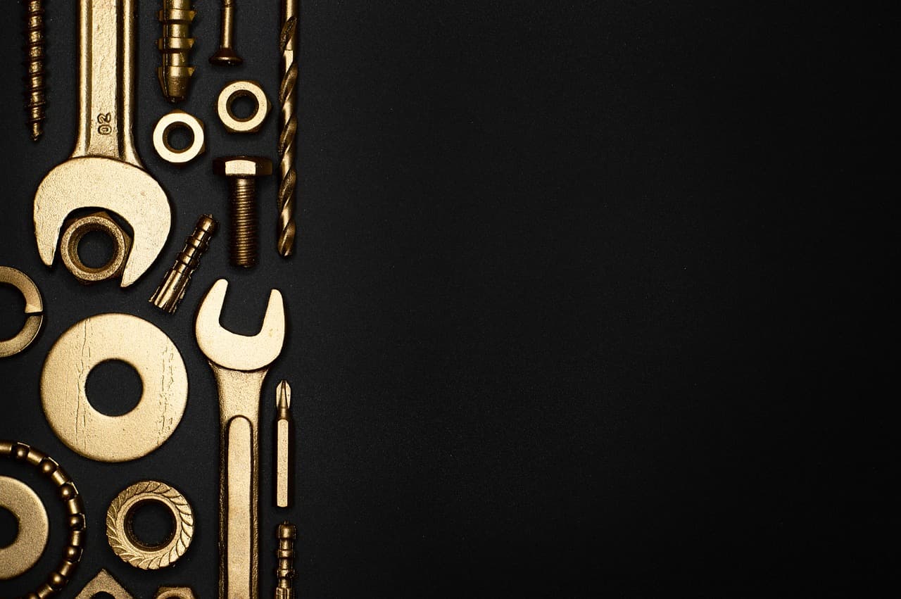 Brass spanners, washers and bolts laid out on black